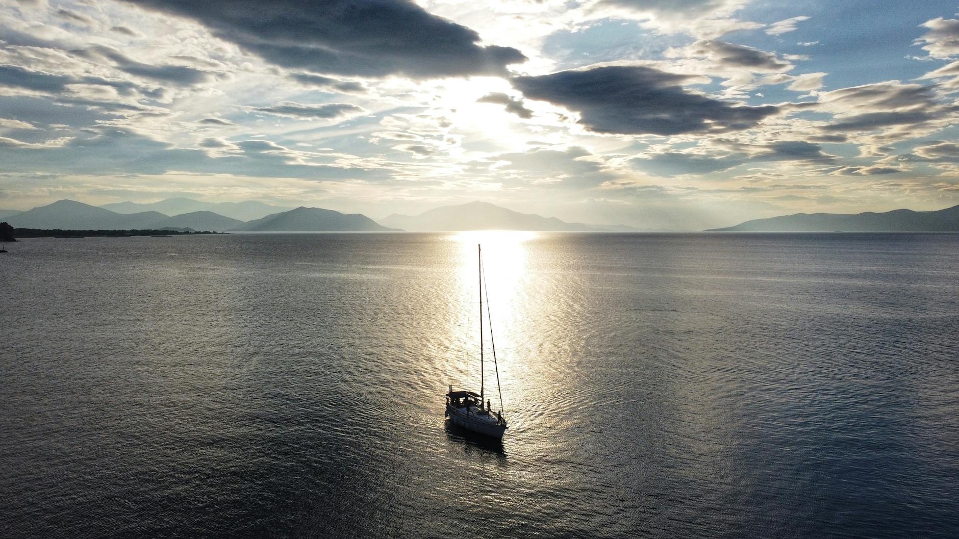 aerial photography of a sailing boat on the ocean during sunrise